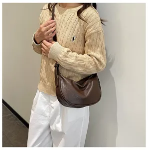 Primo piano di una elegante borsa a tracolla in pelle PU marrone indossata in un look.