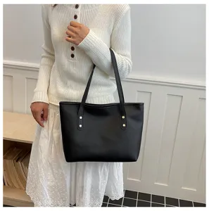Primer plano detallado del bolso tote de cuero negro, mostrando el diseño de las asas.