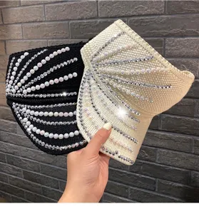 Vista detallada de viseras de punto decoradas con perlas y diamantes, sombrero elegante.