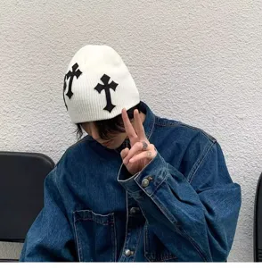 Vue détaillée du bonnet en tricot unisexe avec des écussons croisés noirs, style streetwear.