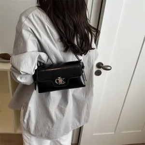 Sac à bandoulière noir en cuir verni classique avec fermoir métallique élégant.