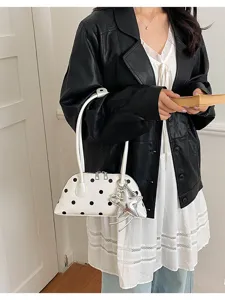Close-up view of white polka dot shoulder bag featuring a chic silver star charm accessory.