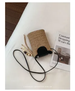 Gedetailleerd overzicht van strooien telefoontas met zwarte lederen flap en houten kralenkwastje.