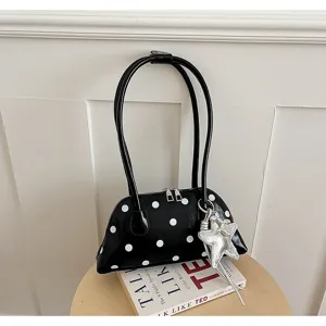 Details van de elegante zwart-witte stippenhandtas met een zilveren sterrenhanger.