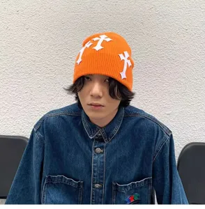 Bonnet en tricot orange avec des patchs de croix blancs, bonnet streetwear stylé et tendance.