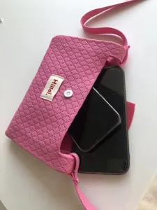 Pink knitted mini crossbody phone bag detail shot, showing practical capacity and texture.