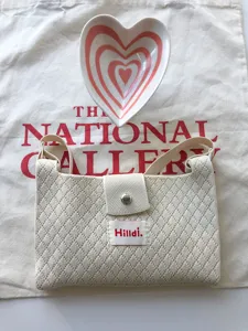 Beige quilted knitted crossbody bag detail, casual phone bag display with heart dish.
