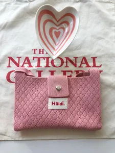 Detailed view of a pink knit crossbody mini bag, featuring a snap button and textured fabric.