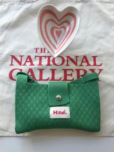 Detail view of the green knit crossbody bag, featuring textured fabric and secure snap button.