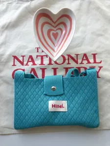 Detail view of a stylish teal knitted crossbody bag with button closure, compact phone purse.