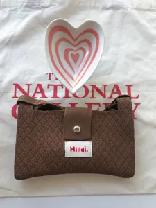 Detailed view of trendy brown knit crossbody bag with heart ceramic dish, stylish travel mini purse.