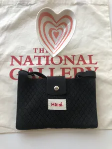 Black knitted crossbody bag with magnetic snap and woven label, trendy small phone purse.