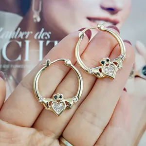 Detailaufnahme der goldfarbenen Claddagh-Creolen mit Kristallherz und Krone im Detail.