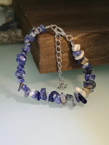 Dettaglio bracciale con pietre naturali, gioiello di perle blu irregolari con catenina estesa.