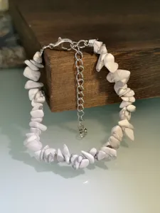 Vista dettagliata del bracciale in pietra naturale bianca irregolare con catena di estensione.