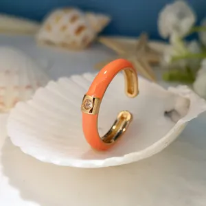 Dettaglio anello in zircone placcato oro con brillante design in smalto arancione vivace.
