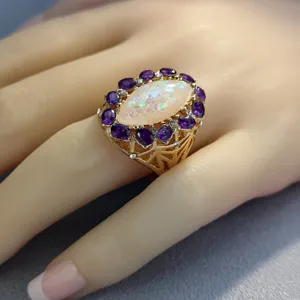 Elegante anello statement dorato con prezioso opale iridescente e pietre viola per stile chic.