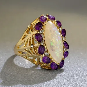 Primo piano dettagliato di un elegante anello in oro con opale marquise e pietre viola.