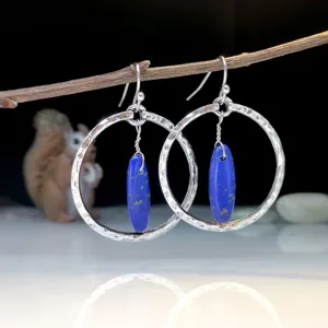 Primo piano dettagliato di orecchini a cerchio in argento martellato con pietra di lapis.
