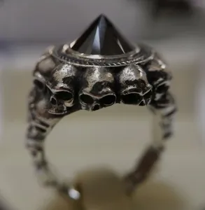 Primo piano dell'anello in argento punk gotico con intagli di teschi e gemma piramidale nera.