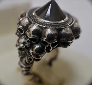 Dettagliato primo piano di un anello teschio punk rock vintage in argento con gemma piramide nera.