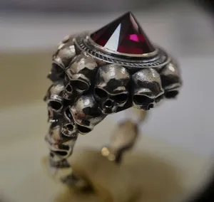 Primo piano dettagliato dell'anello teschio punk gotico con una splendida gemma rossa conica.
