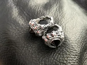 Primo piano di anello teschio punk in argento con pietra preziosa nera piramidale.