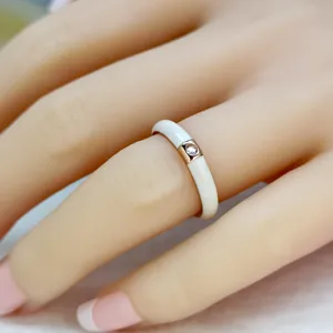 Primo piano dettagliato dell'elegante anello in smalto bianco con zircone quadrato dorato.