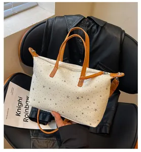 Detailansicht der stylischen Schultertasche mit Sternenmuster und braunen Griffen, groß.