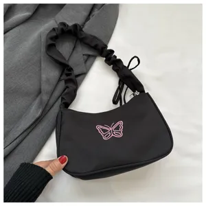 Vista dettagliata della borsa a spalla in nylon nero con ricamo farfalla rosa e manico arricciato.