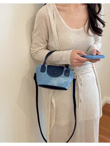 Detailansicht der modischen Jeans-Leder-Umhängetasche, getragen von einem Model im Innenbereich.