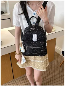 Detail shot of black star print mini backpack with cute white bunny patch and pendant.