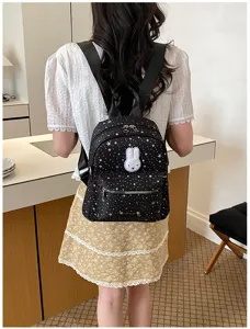 Detailed shot of a black star print mini backpack featuring a cute bunny patch and straps.