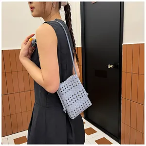 Vue détaillée d'un sac bandoulière tissé bleu clair pour téléphone portable en été.