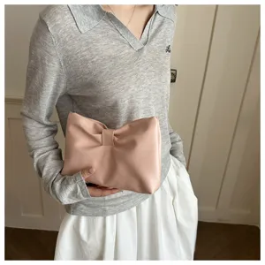 Pink bow clutch bag detail shot, showcasing the soft PU leather material and exquisite pleats.