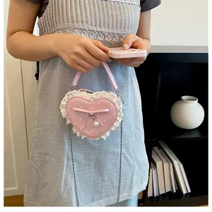 Vue détaillée d'un mini sac à main rose en forme de cœur avec dentelle, nœud et perle.