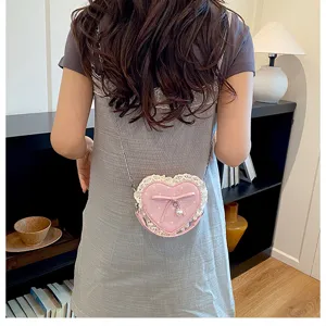 Détail de sac bandoulière cœur rose mignon avec volant en dentelle, nœud et perle.