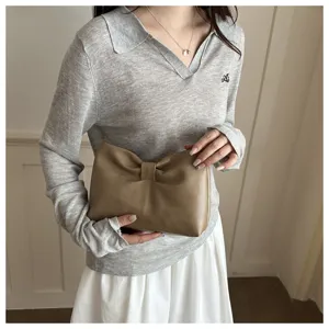 Detail shot of stylish khaki bow clutch bag, elegant underarm bag design for women daily wear.