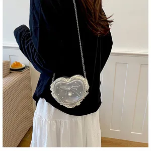 Détail de mini sac bandoulière en forme de cœur, bordure en dentelle et nœud en perle.
