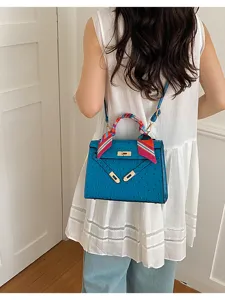 Ostrich grain handbag detail, elegant blue shoulder bag with twist lock and twilly scarf.