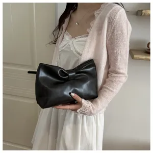 Minimalist black leather bow clutch detail, elegant underarm shoulder bag for daily commute.