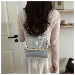 Detailed view of the cute polka dot bunny backpack with lace and pearl charm worn indoors.