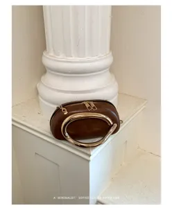 Brown retro shoulder bag detail with unique golden ring handle and minimalist aesthetic.
