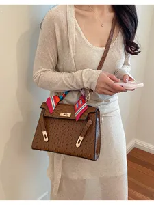 Brown ostrich textured Kelly bag with colorful silk scarf for daily commuter fashion style.
