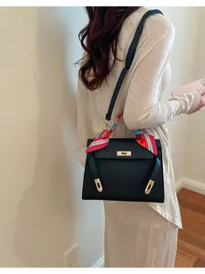 Black ostrich texture Kelly bag with colorful scarf handle detail and gold hardware for women.