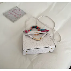 White ostrich pattern Kelly handbag detail showcasing structured design and metal hardware.