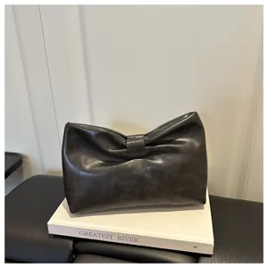 Pochette en cuir gris foncé avec nœud élégant, accessoire de mode stylé et minimaliste.