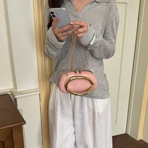 Trendy pink shoulder bag for women, featuring a unique gold ring handle and chain strap.