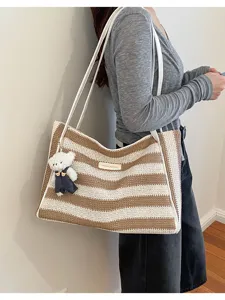 Détail du sac cabas en tricot rayé avec pendentif ours mignon et bandoulières solides.
