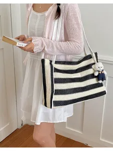 Vue détaillée du sac cabas en paille noir et blanc avec un joli pendentif ours d'été.